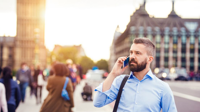 A man speaking on a mobile phone with Westminster in the background.
