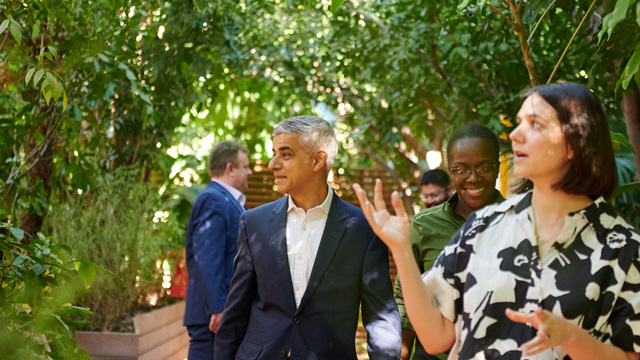 Sadiq Khan and a group of people walk through a garden filled with greenery