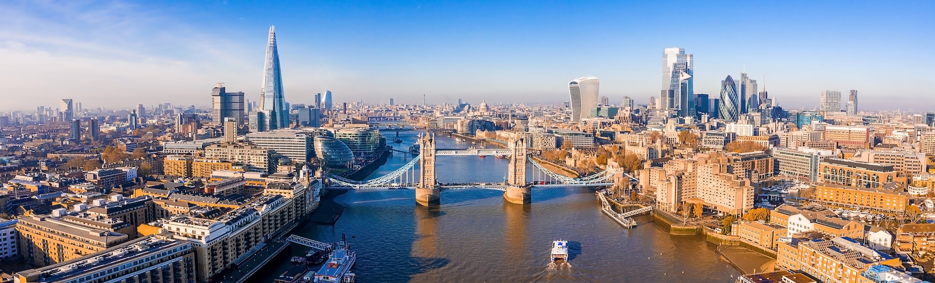 Aerial view of the Thames and Tower Bridge and the London skyline under a blue sky