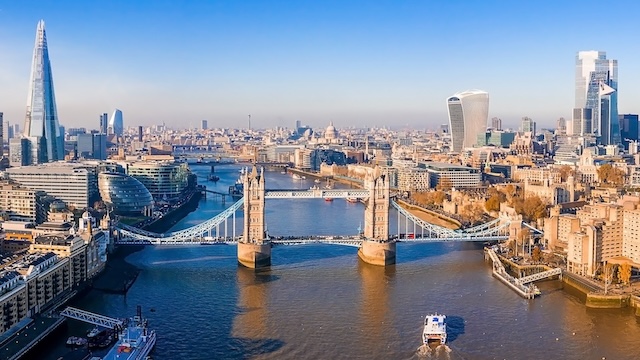 Aerial view of the Thames and Tower Bridge and the London skyline under a blue sky