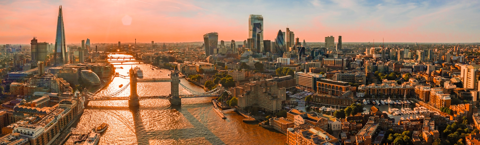 London skyline in orange glow at sunset, viewed from above, with The Shard, Tower Bridge, the Thames and the City all in sight.