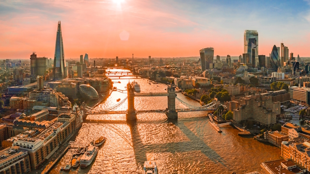 London skyline in orange glow at sunset, viewed from above, with The Shard, Tower Bridge, the Thames and the City all in sight.