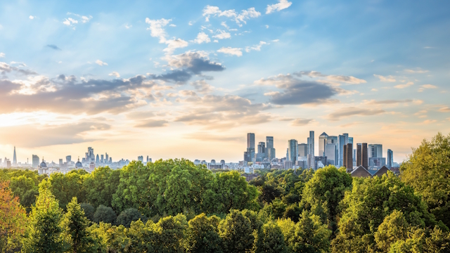 Greenwich Hill view on London skyline, with skyscrapers in the distance and trees in the foreground.