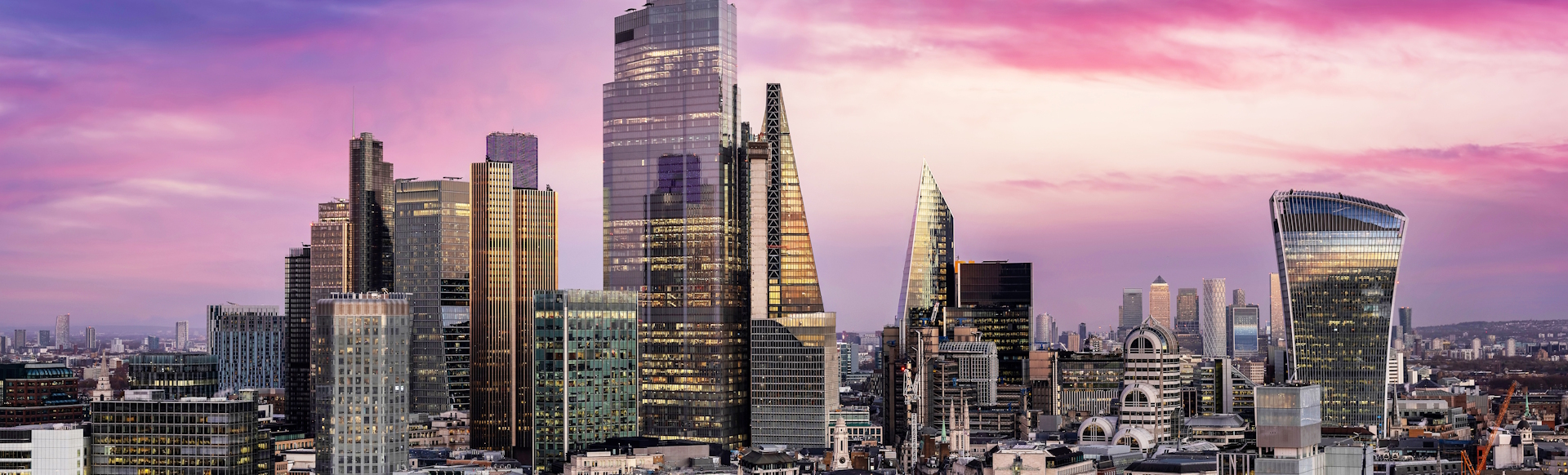 City of London skyline with skyscrapers and purple-hued sky.