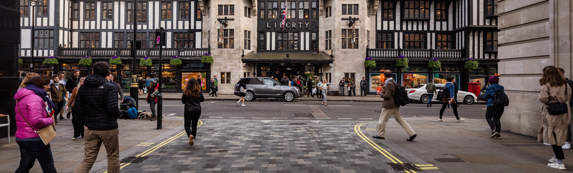 People walking and crossing the street opposite Liberty department store in London on a winter's day.
