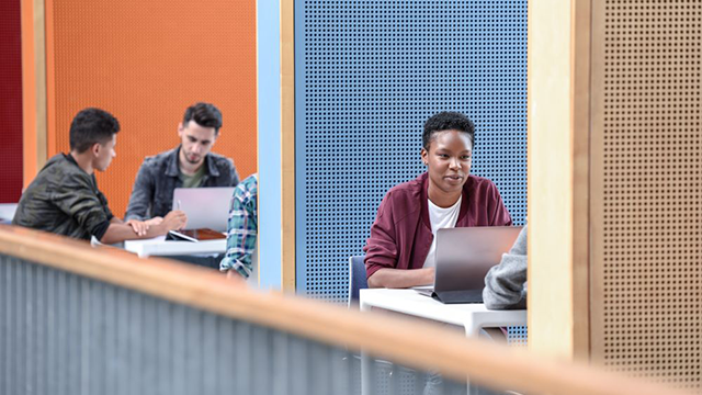 Groups of students with laptops sitting in different colour booths