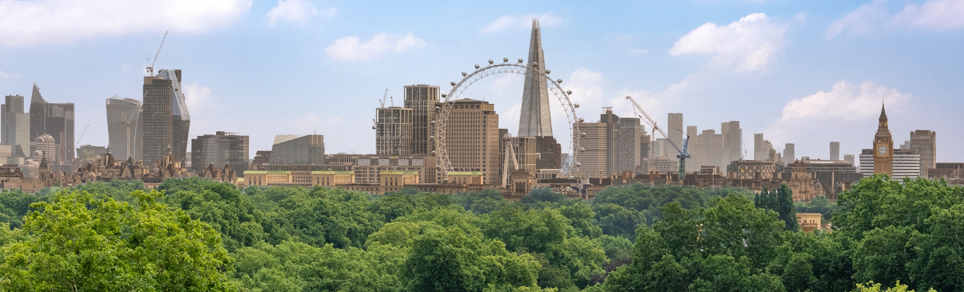 London skyline featuring London Eye, The Shard and Big Ben, with park in foreground.