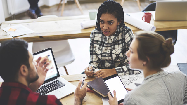 A group of three people having a meeting in a contemporary office space in London.
