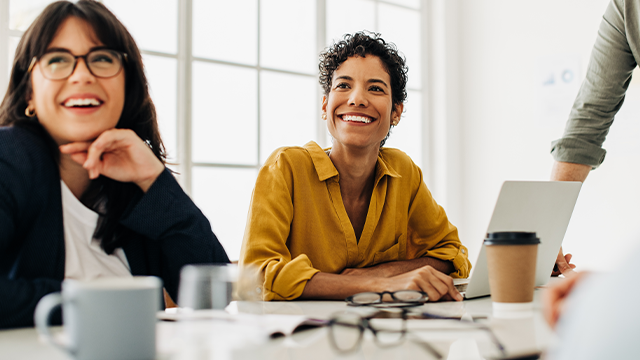 Two women smiling in a boardroom meeting