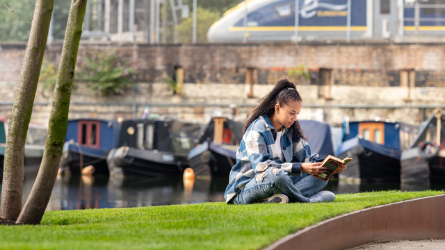 A person reads a book next to Regent's Canal in King's Cross