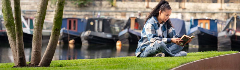 A person reads a book next to Regent's Canal in King's Cross
