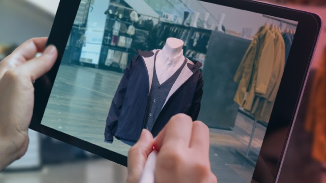 A person holds a tablet and uses it to shop online for clothes