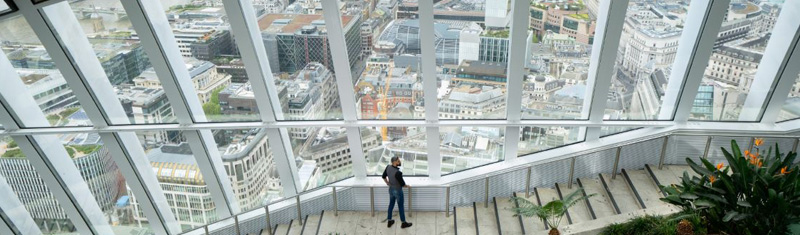 A man standing at a window overlooking the City of London.