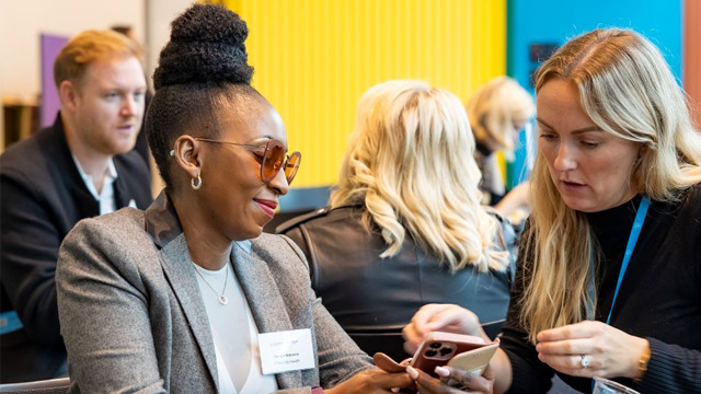 Two women sharing contact details at a business event. 