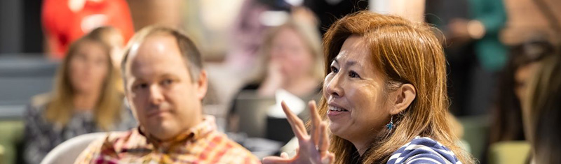  A woman asking a question during a conference.