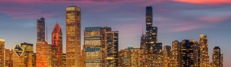 A dusk scene of Chicago's downtown skyscrapers with a blue and pink sky in the background.