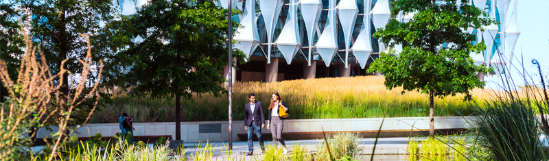 Two people stroll along the pathway through Embassy Gardens