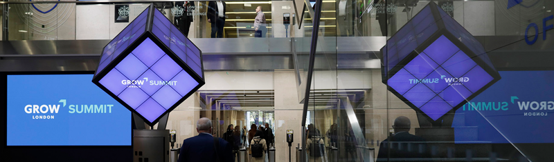 A building lobby with luminous blue and purple GROW Summit branded decorations.