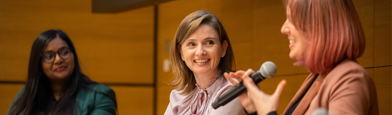 Three panelists on stage and speaking during a conference 