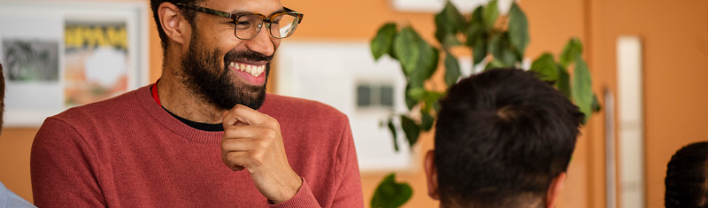 A smiling man with glasses having a conversation during a business networking event.