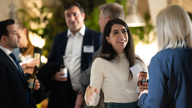 Two women in business attire speaking during a networking event.