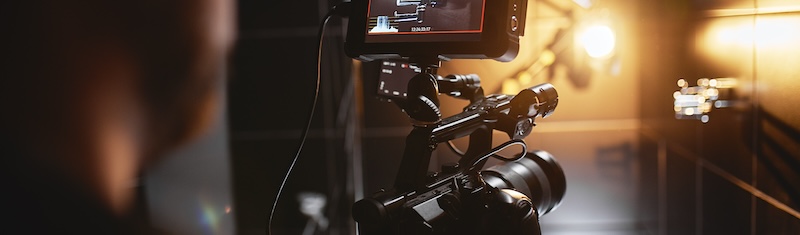 Professional video camera with monitor filming in a warmly lit studio