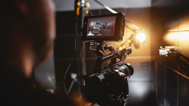 Professional video camera with monitor filming in a warmly lit studio