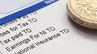 A close up of a tax form and a pound coin on top of the form.