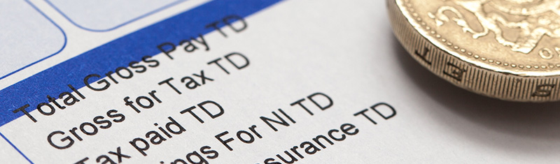 A close up of a tax form and a pound coin on top of the form.