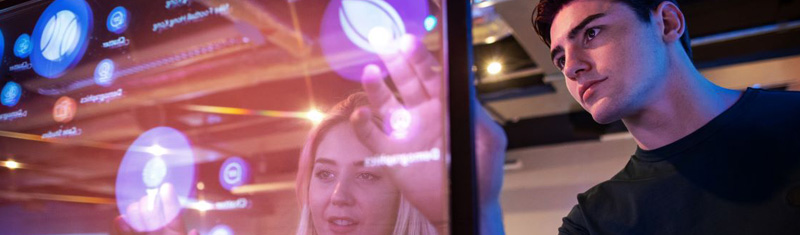 A man and a woman using a glass touchscreen.