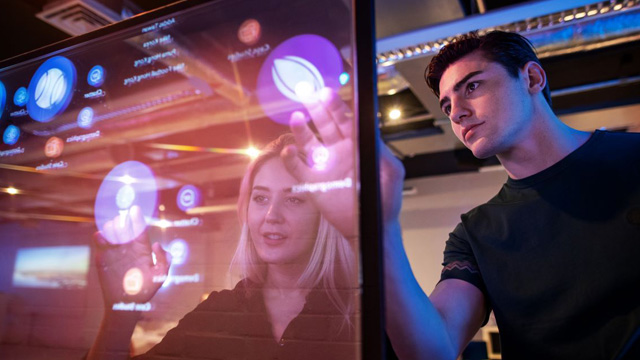 A man and a woman using a glass touchscreen.