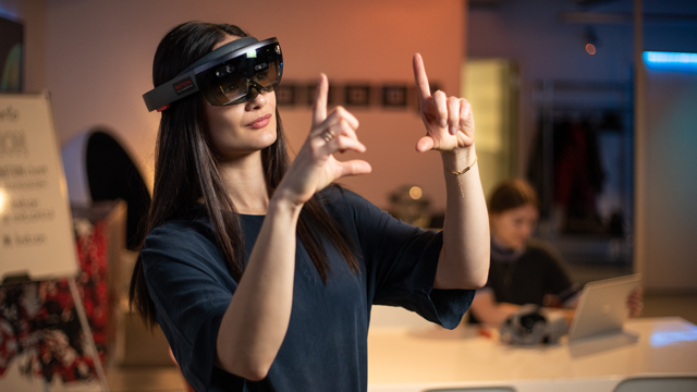 A woman using a virtual reality headset and making gestures with  her hands.