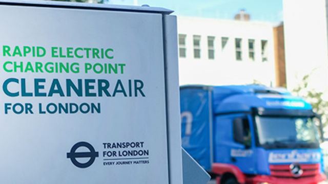 A sign that says "rapid electric charging point, cleaner air for London", a lorry in the background