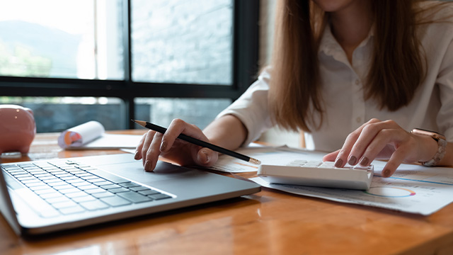 Businesswoman using a laptop and calculator.